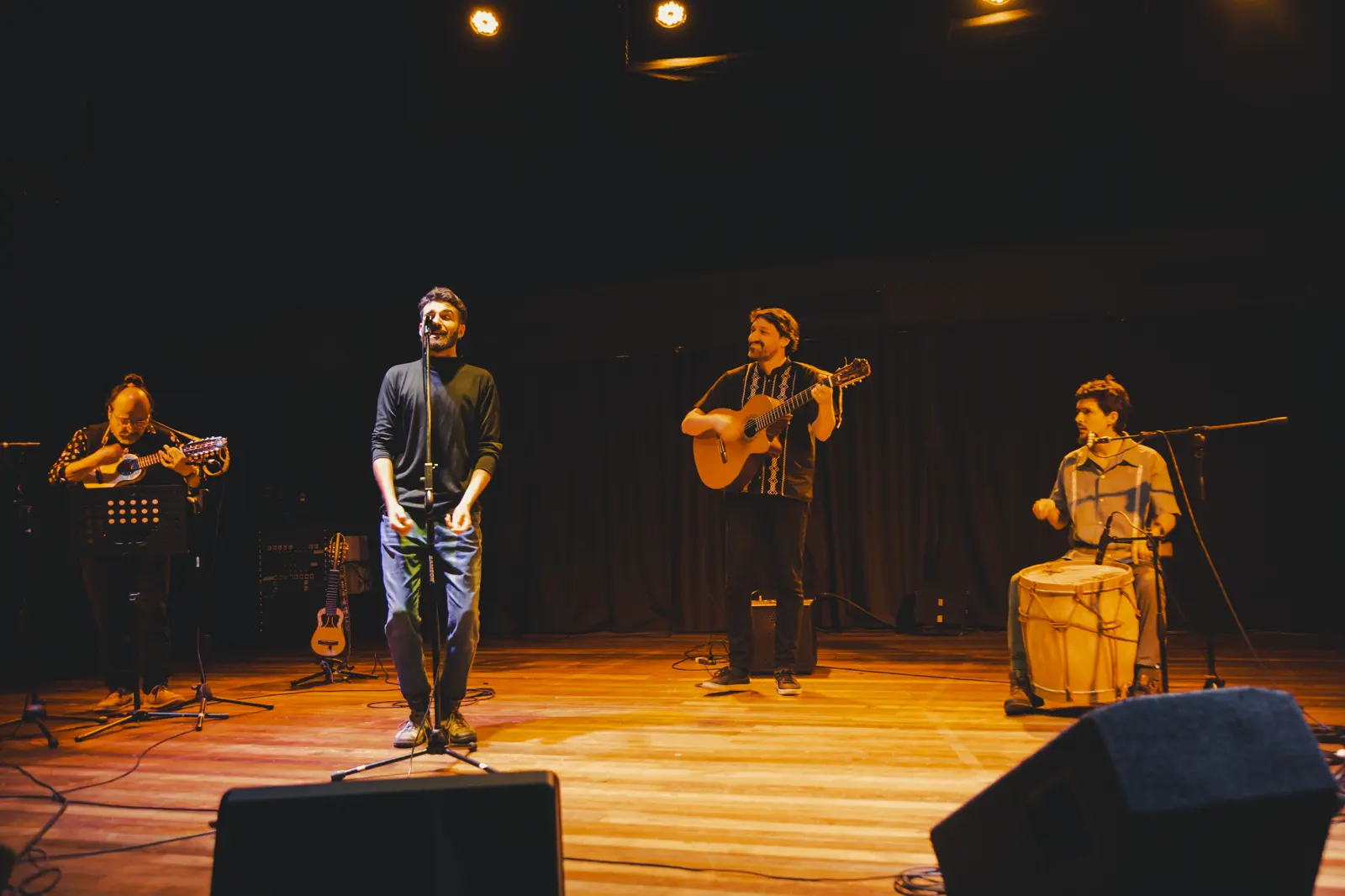 Bruno Meschi sings standing at the centre of the stage, accompanied by three musicians