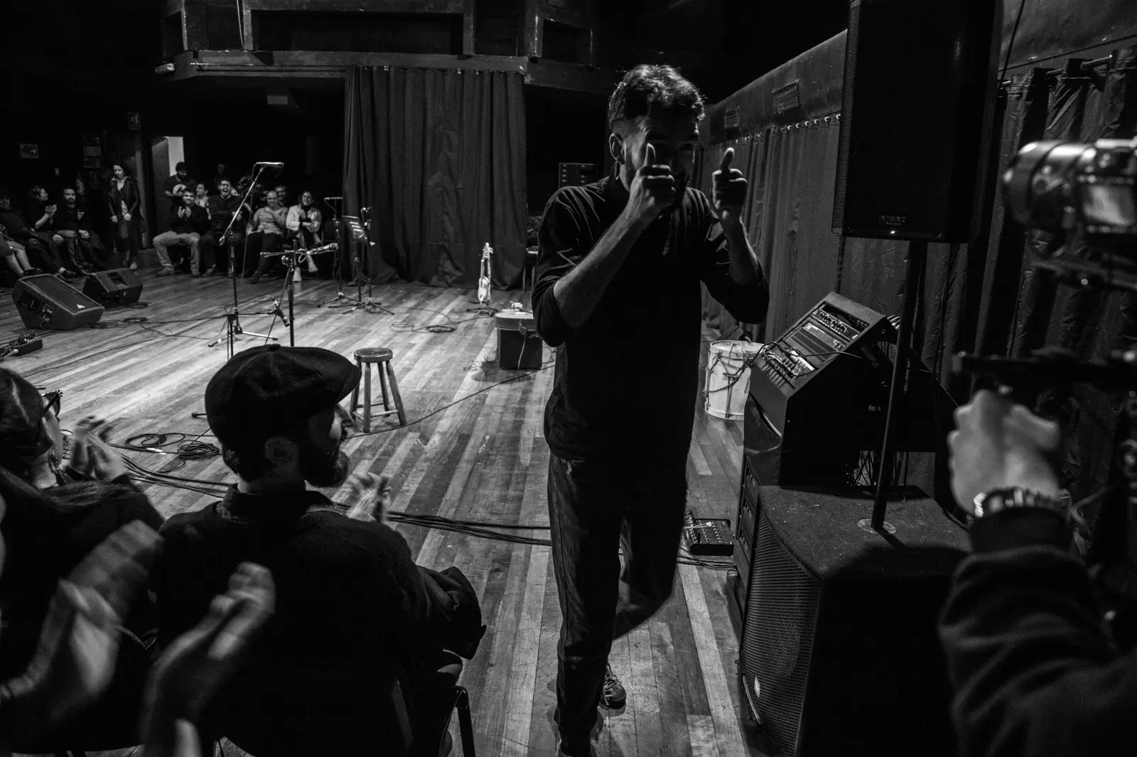In black and white, a photographer captures the concert from the side of the stage